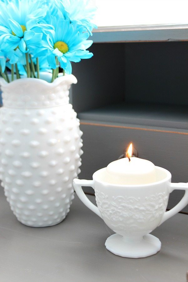 Flowers and candle in milk glass on the bedside table at refreshrestyle.com