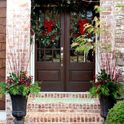 Welcome to our home at Christmas, the double doors have matching wreaths and garland above with natural elements in the flower pots.