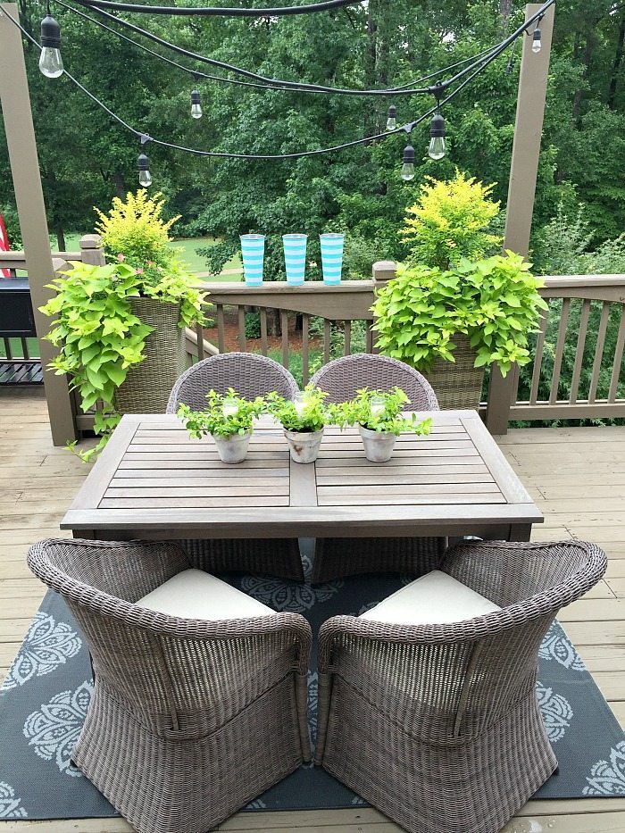 Perfect outdoor dining space with lights, candles and greenery - centerpiece of candles in garden pots