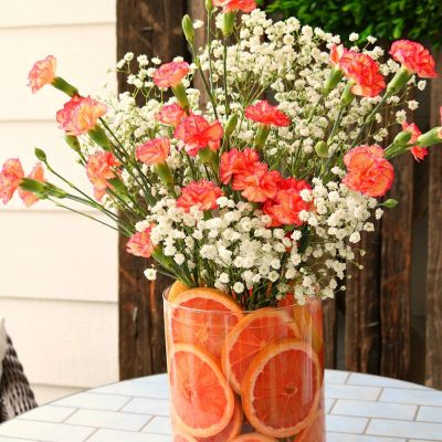 Red grapefruit and pink carnations make a sweet smelling floral arrangement
