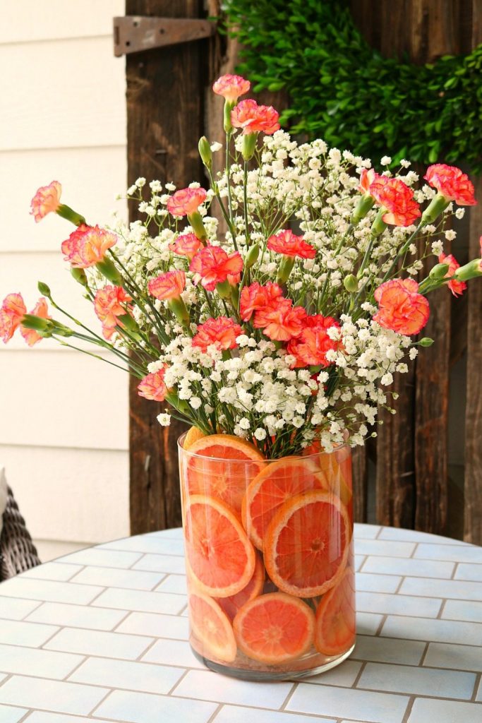 Red grapefruit and pink carnations make a sweet smelling floral arrangement