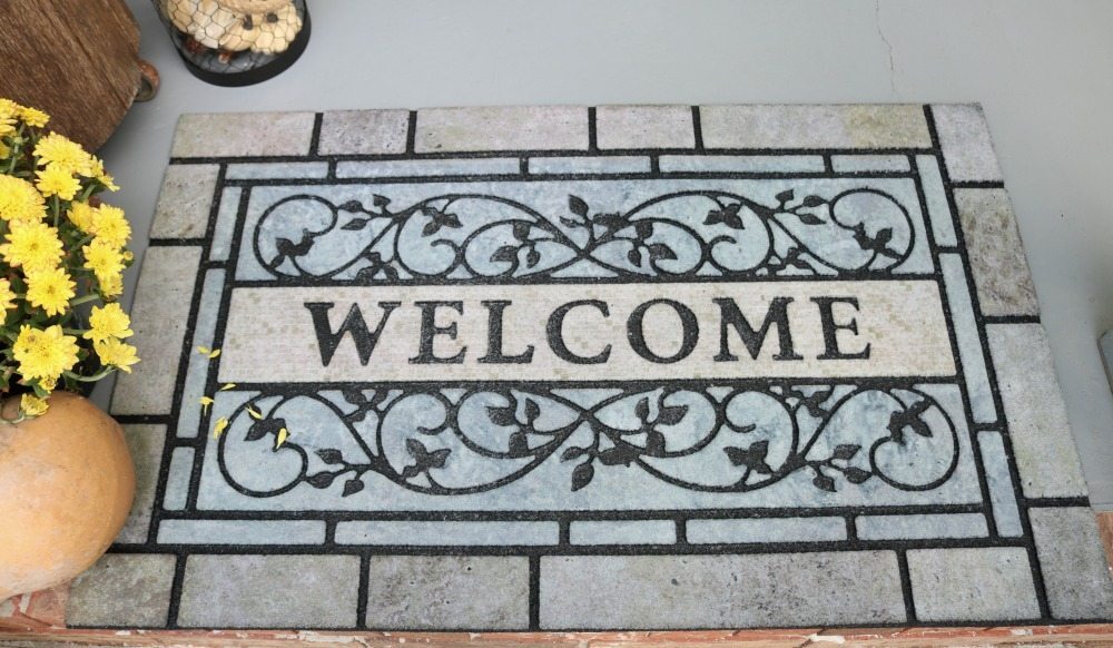 Gray and blue welcome mat on a painted gray porch